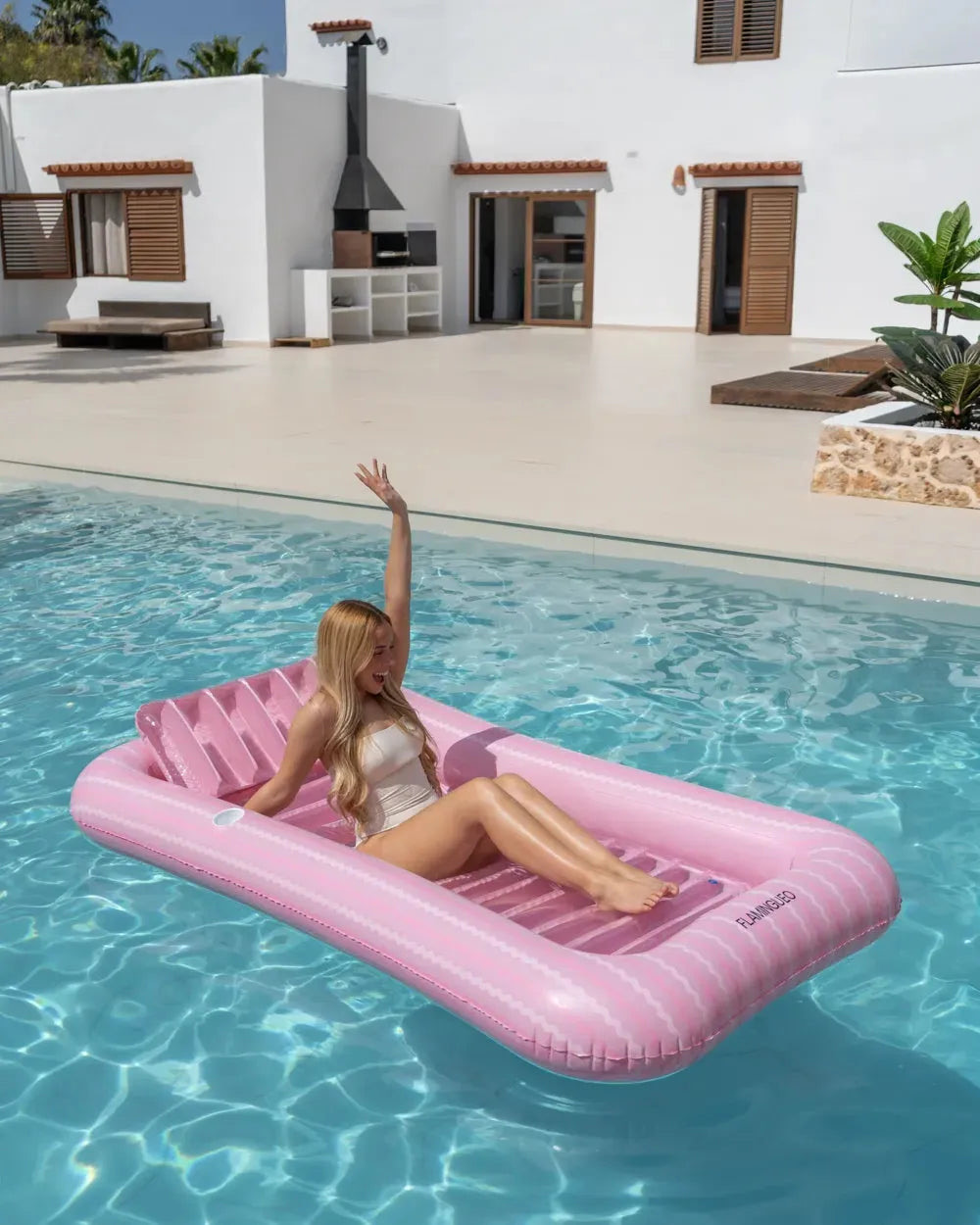 Mulher sentada e relaxada na piscina insuflável individual rosa com almofada