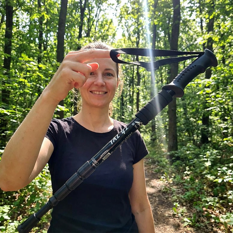 Mulher a usar o bastão de caminhada num trilho na floresta
