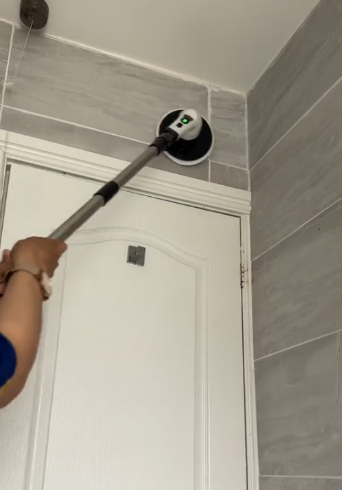 Escova elétrica com haste telescópica a limpar o teto e os azulejos altos da casa de banho